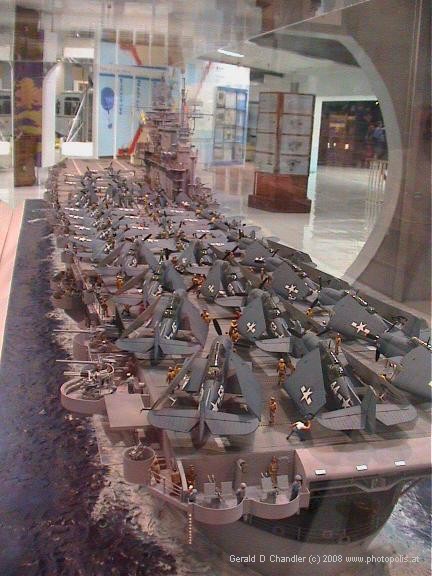 Model of WWII aircraft carrier with many airplanes on flight deck